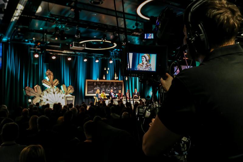 Mennesker p&aring; konferanse. Paneldebatt p&aring; scenen.