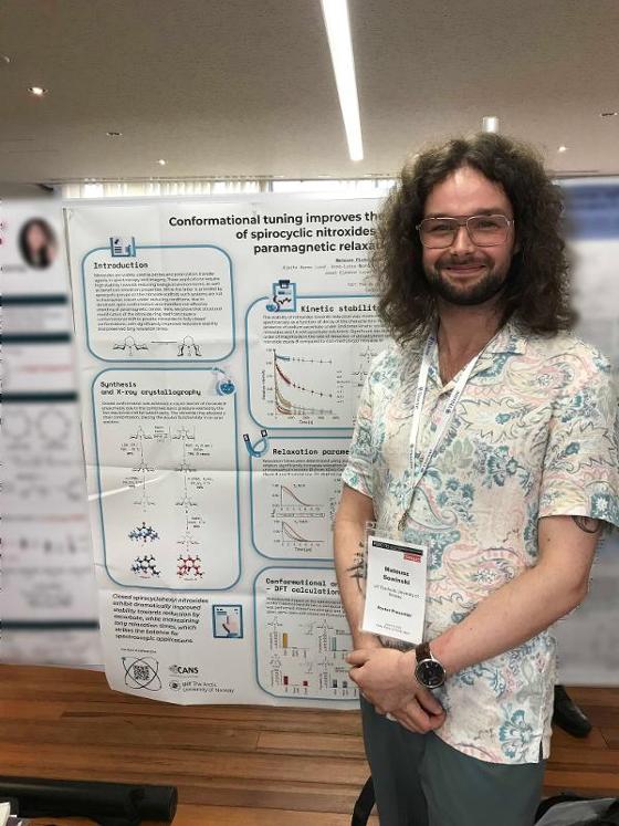 Mateusz standing with his poster, smiling