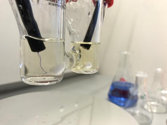 Laboratory glassware containing solutions of different colours, connected into a model battery