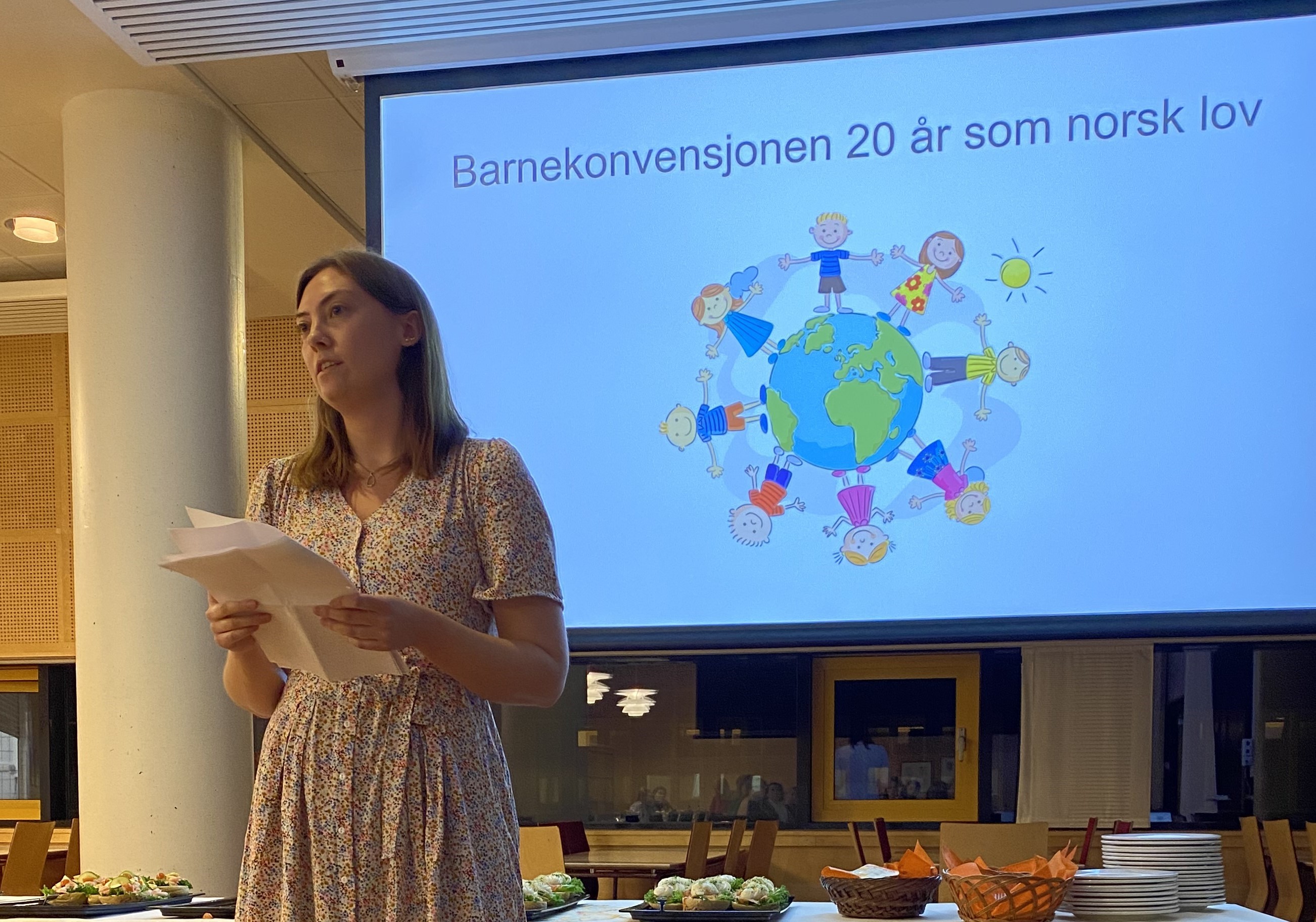 Fredrikke holder et ark og st&aring;r foran en skjerm.