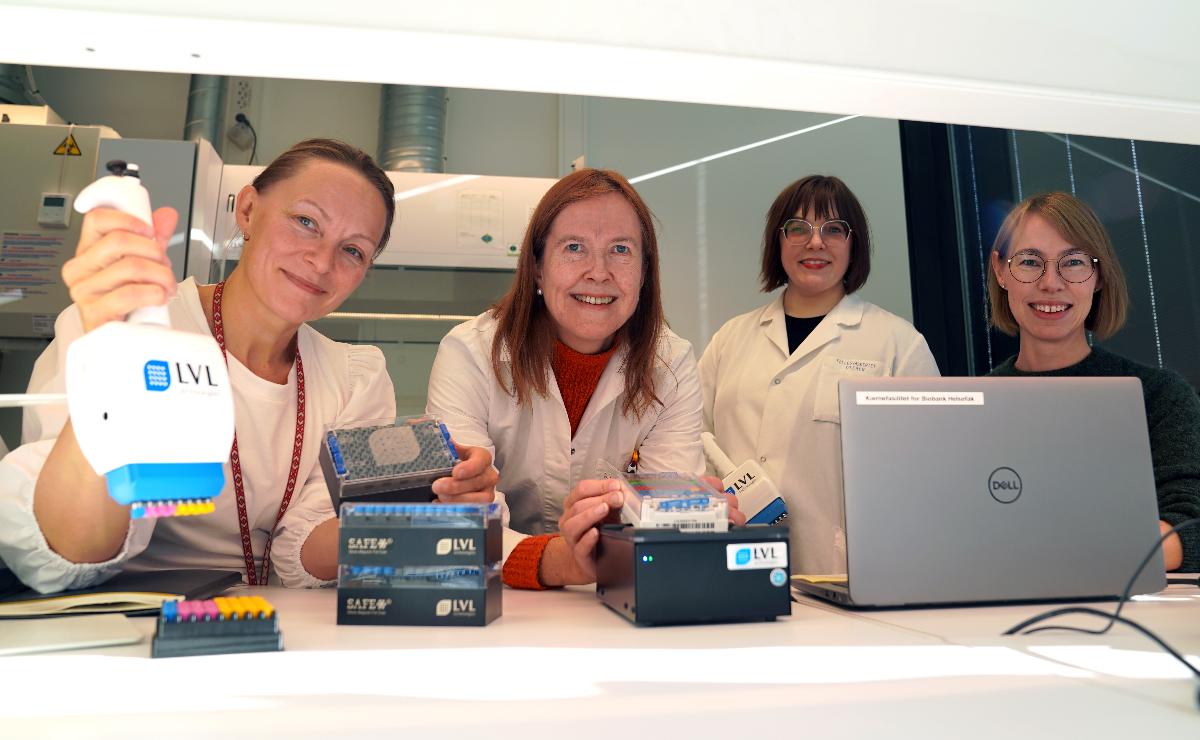 Fire mennesker i laboratorium smiler til kamera