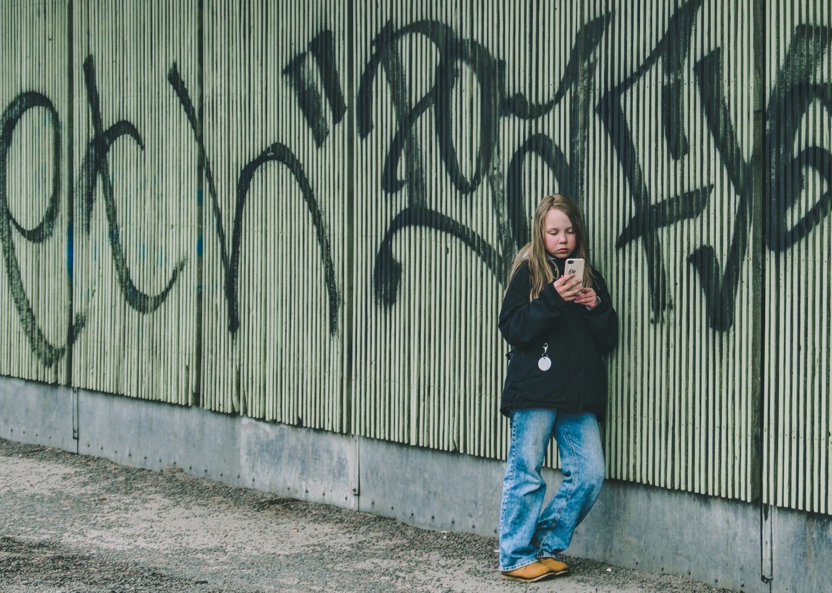 jente som st&aring;r &aring; ser p&aring; telefonen