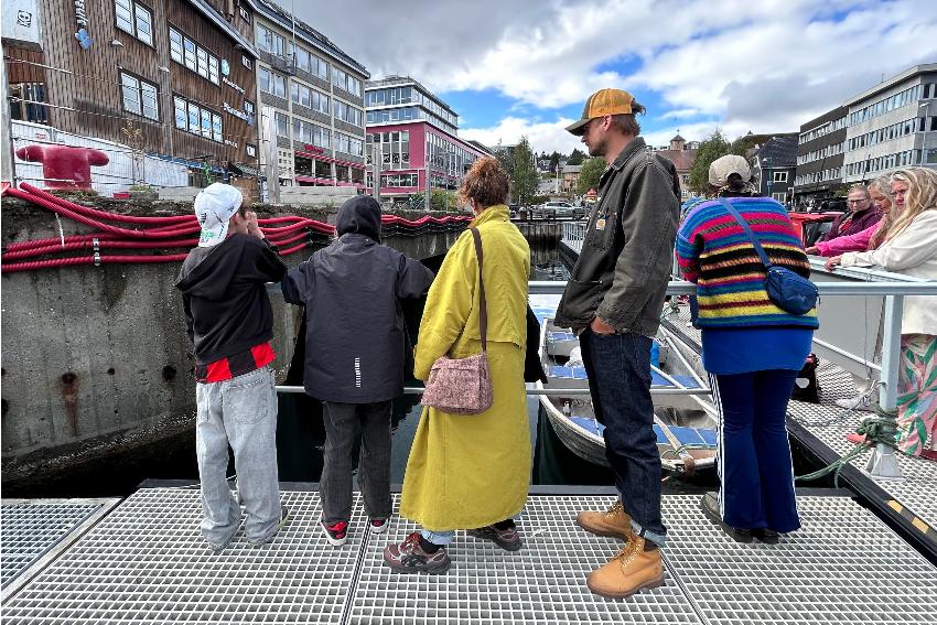 Personer som st&aring;r ved en brygge.