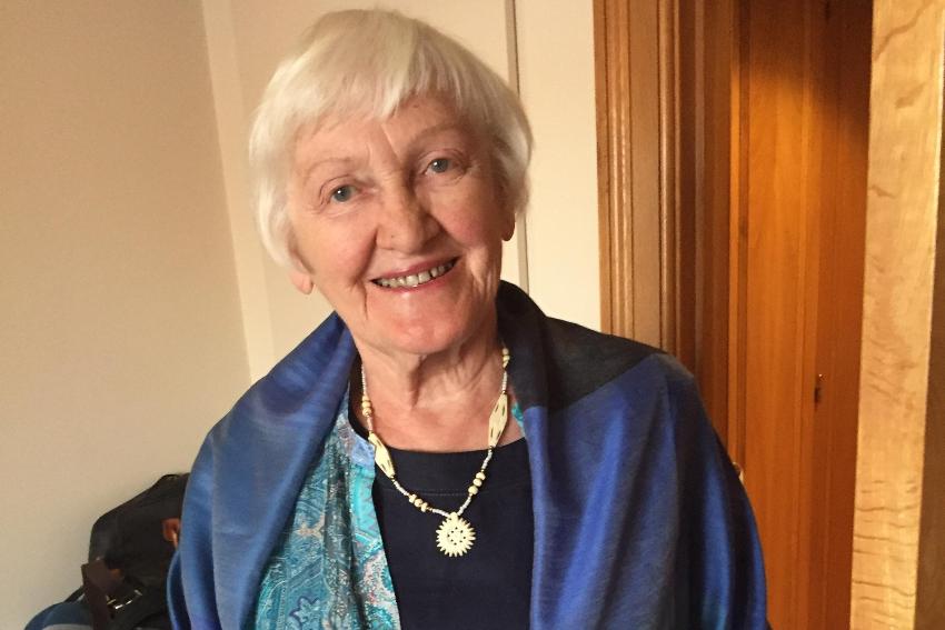 En eldre kvinne smiler mot kamera